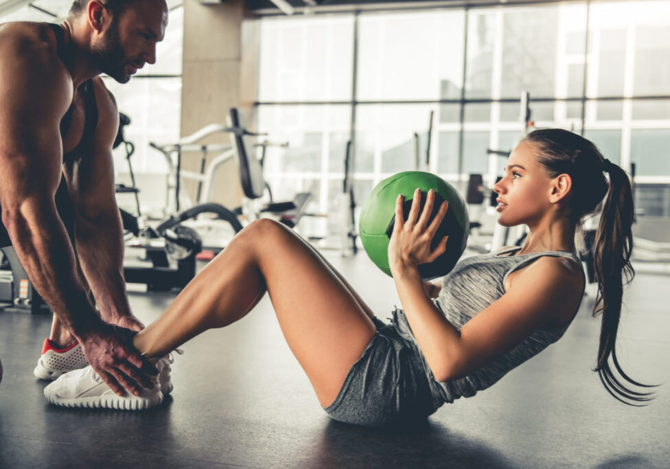 Sports people are working out with fitness balls in gym.